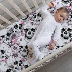 a baby laying in a crib with skulls on it