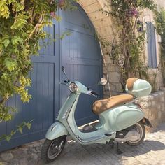 a scooter parked in front of a blue door with flowers growing on it