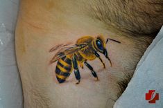 a close up of a bee on the side of a man's stomach with blue eyes