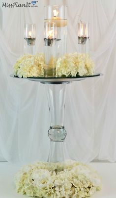 a cake stand with candles and flowers on it for centerpieces or wedding decor