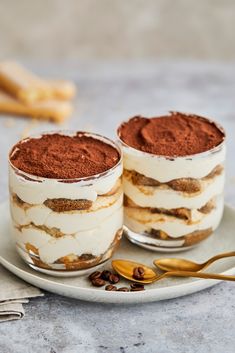 two desserts are on a plate with spoons