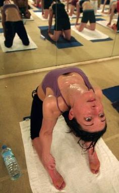 a woman is doing yoga on a mat in the middle of a room full of people