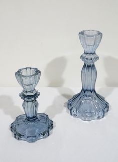 two clear glass candlesticks on a white surface