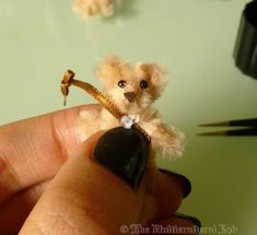 a tiny teddy bear is holding onto a string