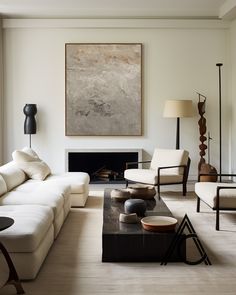 a living room filled with furniture and a painting hanging on the wall over a fire place