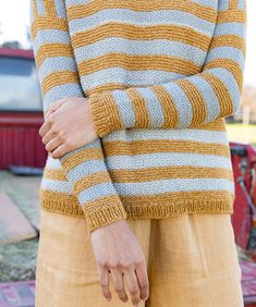 a woman standing in front of a red truck wearing a yellow and gray striped sweater