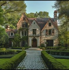 a large brick house surrounded by trees and bushes with a stone walkway leading to the front door