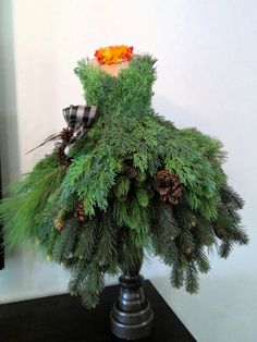 a vase filled with evergreen and pine cones