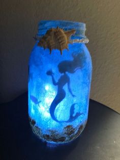 a blue glass jar with a silhouette of a mermaid on it