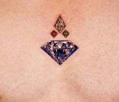 a close up of a person's chest with three different colored diamonds on it