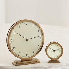 an alarm clock sitting on top of a table next to a small round object with two hands