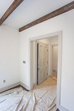 an empty room with white walls and wood beams