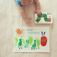 a baby is laying on the floor next to a book and handprinted picture