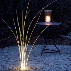 a lit candle sitting on top of a table in the middle of a field at night