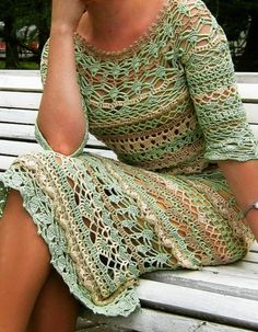 a woman is sitting on a bench talking on her cell phone while wearing a crocheted dress