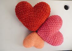 two crocheted hearts sitting next to each other on top of a cutting board