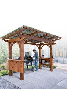 a man standing in front of a wooden gazebo on top of a stone patio