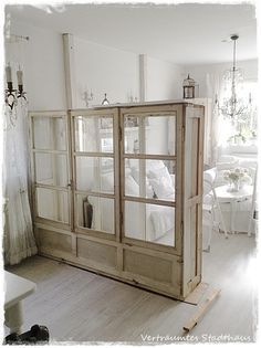 a room with white furniture and windows in the corner, all made out of wood