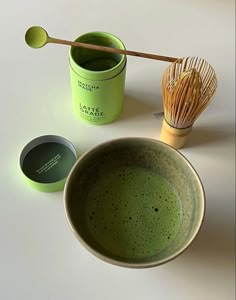 a green cup and whisk on a white table