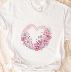 a white t - shirt with pink flowers in the shape of a heart on it