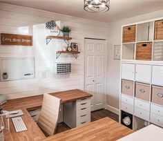 a home office with white cabinets and wooden desks in the center, along with baskets on the wall