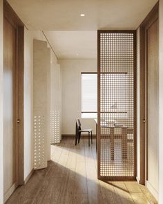 an empty room with wooden floors and white walls, is seen from the hallway to the dining area