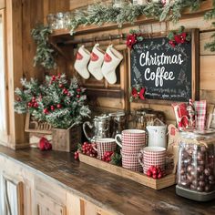 a counter with coffee cups and mugs on it in front of a christmas sign