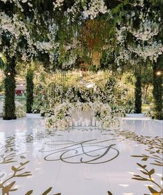 an outdoor wedding ceremony with white flowers and greenery on the floor, surrounded by trees