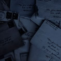 many old envelopes are piled on top of each other in blue hued lighting