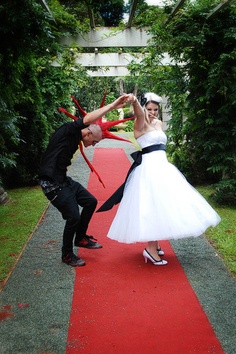 a man and woman are dancing on a red carpet in front of some trees with scissors