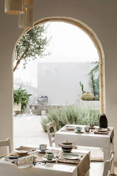 a table with plates and cups on it in front of an arched doorway that leads to a patio