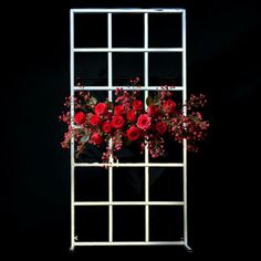 red flowers are arranged in a white trellis on a black background with space for text