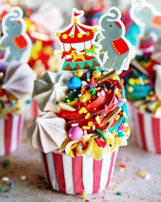 colorful cupcakes with circus decorations on top and sprinkles all over them