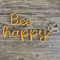 the word bee and happy spelled in yellow thread on a wooden background with two hearts