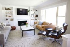 a living room filled with furniture and a flat screen tv mounted on the wall above a fireplace