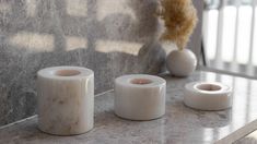 three white vases sitting on top of a counter