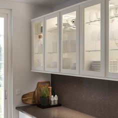 a kitchen with white cupboards and counter tops next to a glass doored window