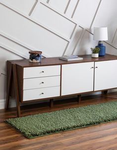 a sideboard with two drawers and a rug on the floor in front of it