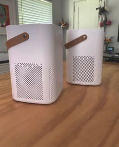 two white speakers sitting on top of a wooden table