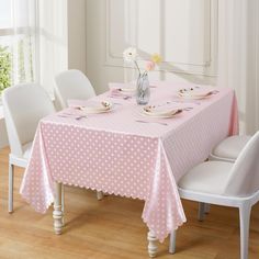 the table is set with pink and white polka dot linens, plates and flowers in a vase