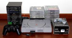 a video game system sitting on top of a wooden table next to stacks of dvd's