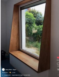 an open window in the corner of a room with trees and bushes seen through it