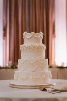 a white wedding cake sitting on top of a table next to a knife and fork