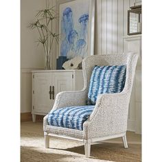 a blue and white chair sitting on top of a rug in a living room next to a painting