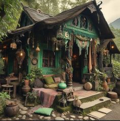 a small green house with lots of plants and decorations on the front porch, along with stone steps