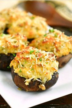 three stuffed mushrooms with cheese and parmesan toppings on a square white plate