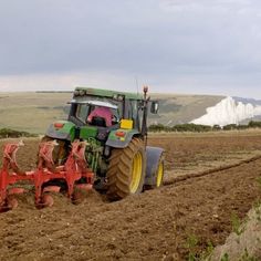 a tractor is plowing the land in front of white cliffs