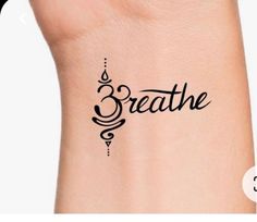 the word breathe written in cursive writing on a woman's wrist tattoo