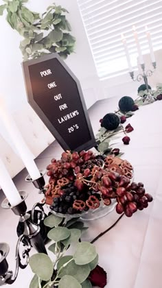 a table topped with grapes and other foods next to two candles on top of it