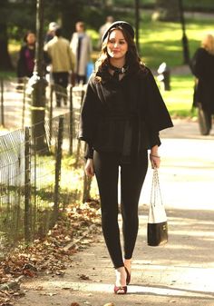 a woman is walking down the street with her hand in her pocket and holding a shopping bag